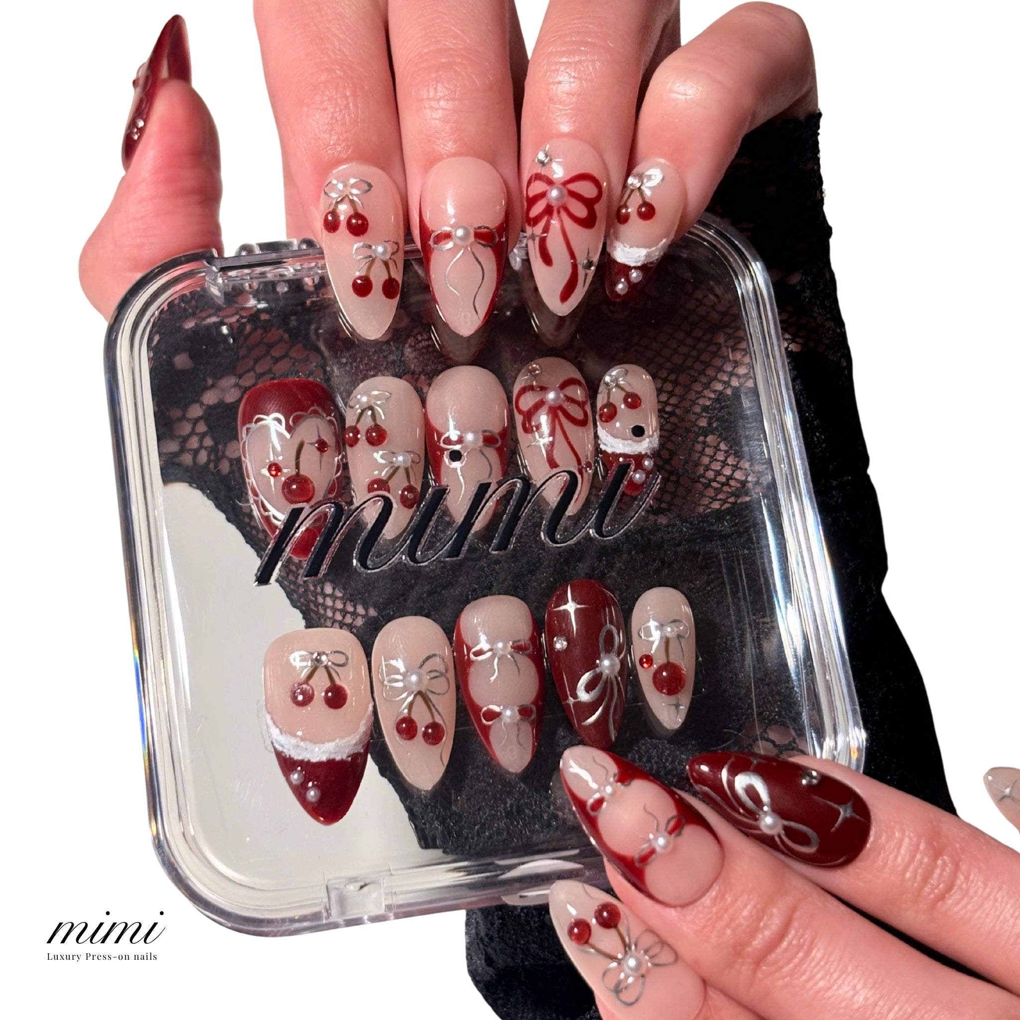 Coffret mimi présentant le set de press-on Cherry Christmas faits main en gel et acrylique, décor cerises rouges, nœuds argentés et motifs Noël.