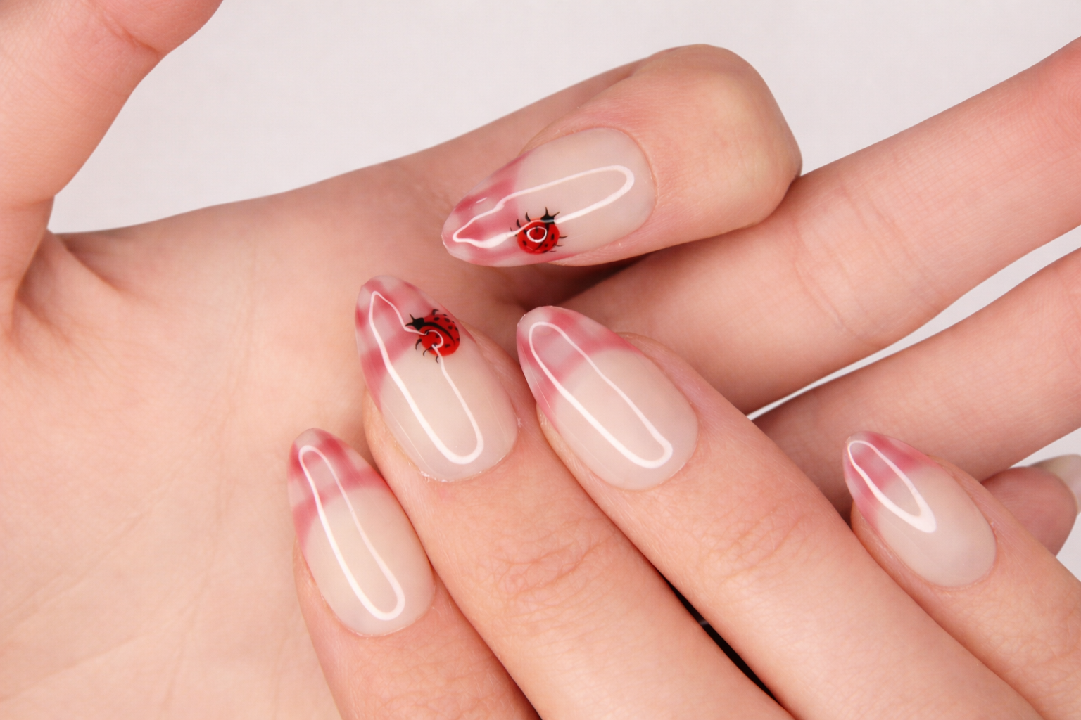 Gros plan sur les détails avec faux ongle press-on coccinelle peinte sur base blanc crème — design Lady Bug fait main — Mimi Press-On