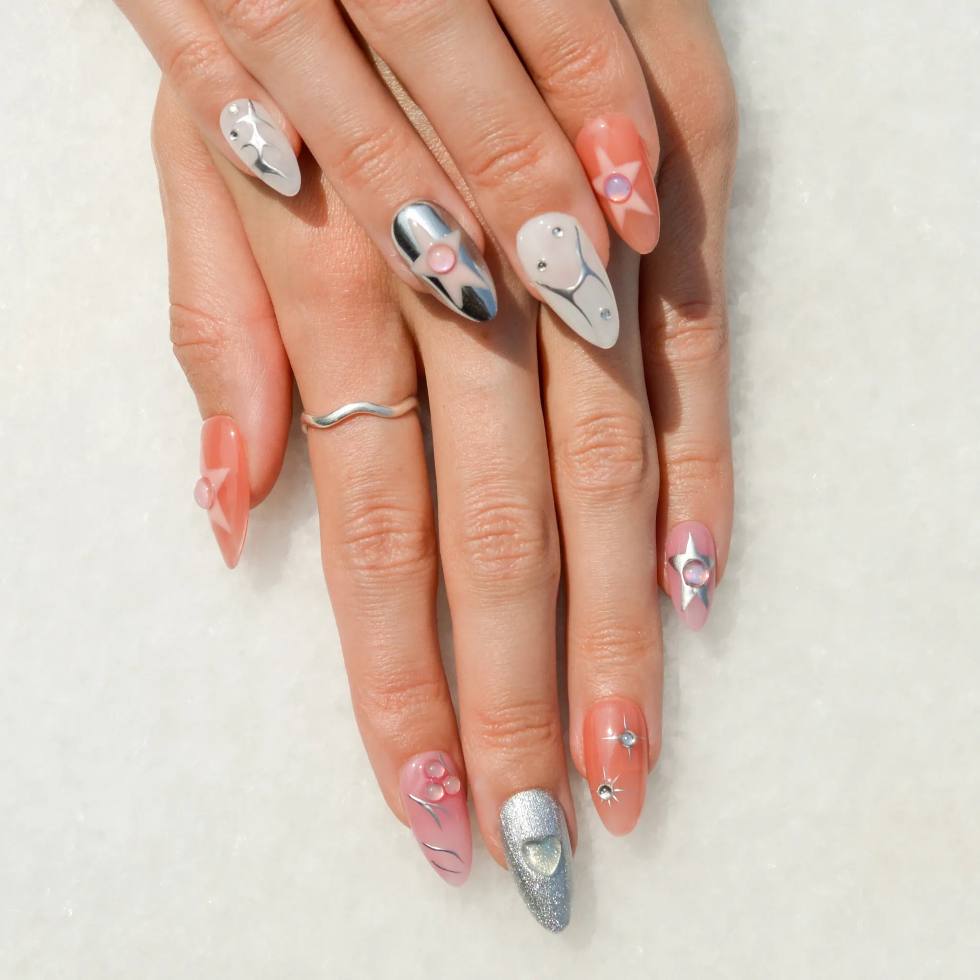 Faux ongles Press-on nails faits main en gel et acrylique Metallic Muse, design 3D rose, violet, blanc et argent avec détails métallisés.