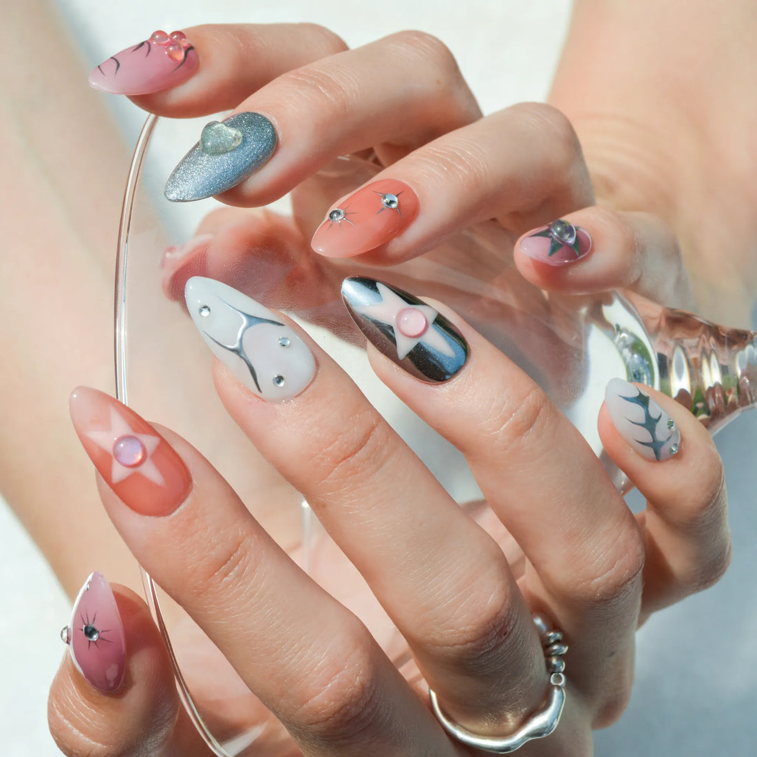 Faux ongles Metallic Muse en gel et acrylique avec finitions métalliques et détails sculptés.