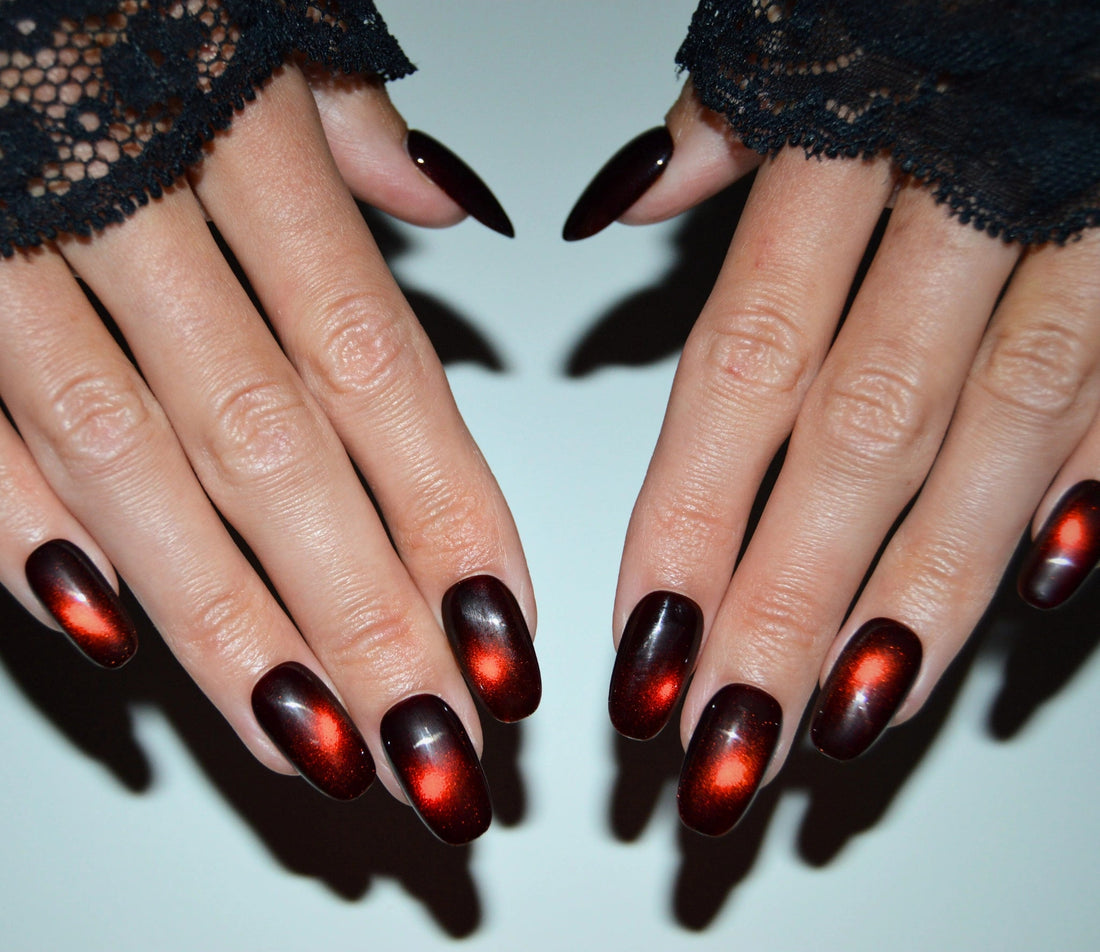 Vue du set complet de press-on nails faits main en gel et acrylique, effet cat eye rouge avec point lumineux central.
