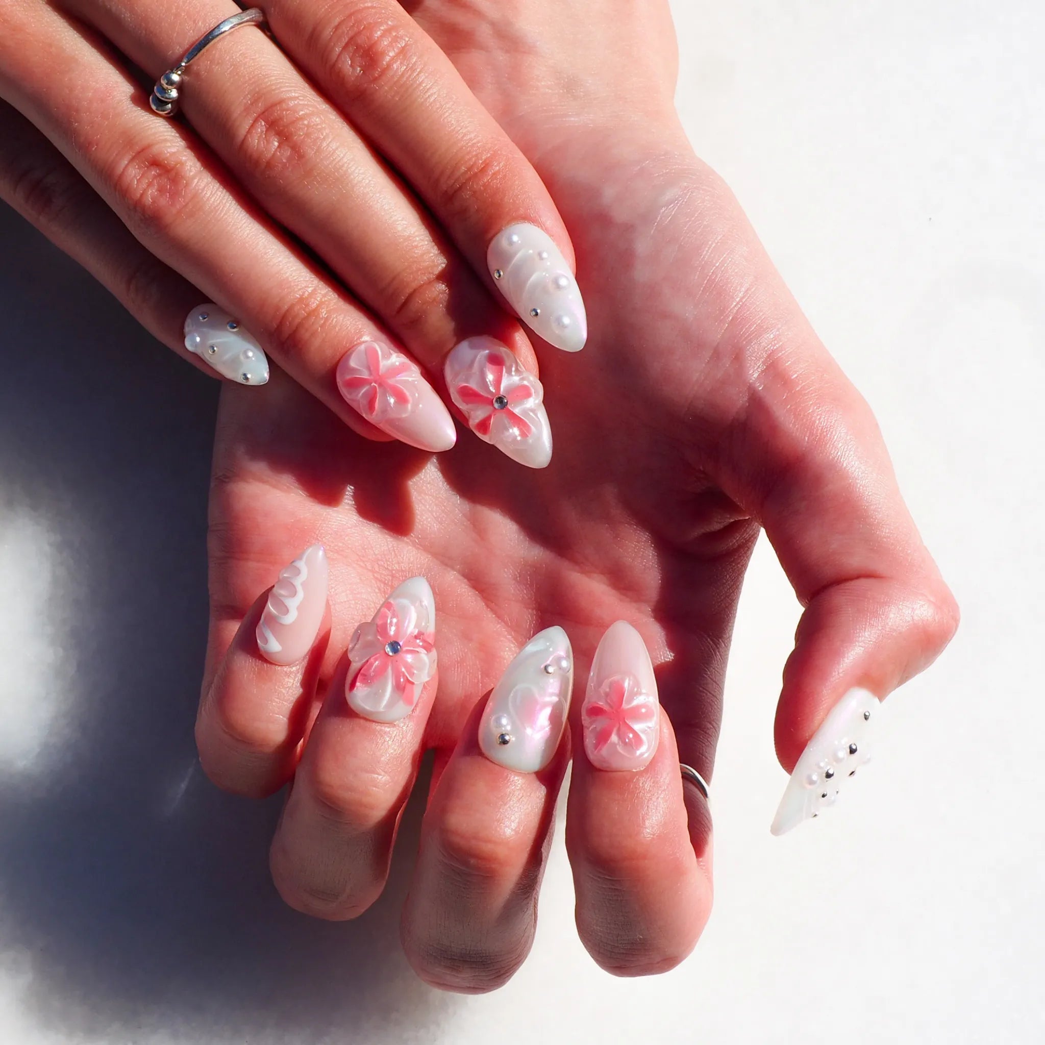 Manucure Pink Fever sur les mains, fleurs 3D roses, perles argentées et dégradés blancs, gel et acrylique faits main.