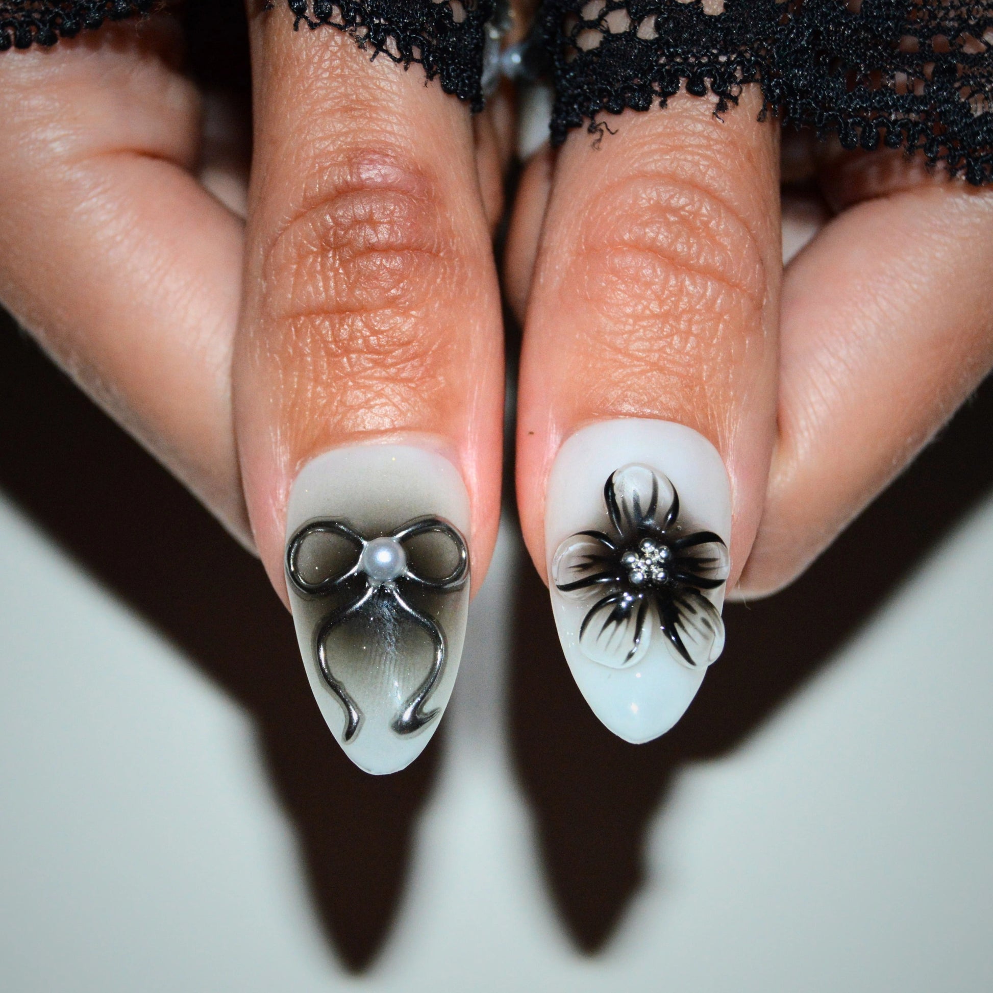 Gros plan sur les press-on nails Shadow Petal faits main, motifs 3D fleur noire et nœud perlé réalisés en gel et acrylique.