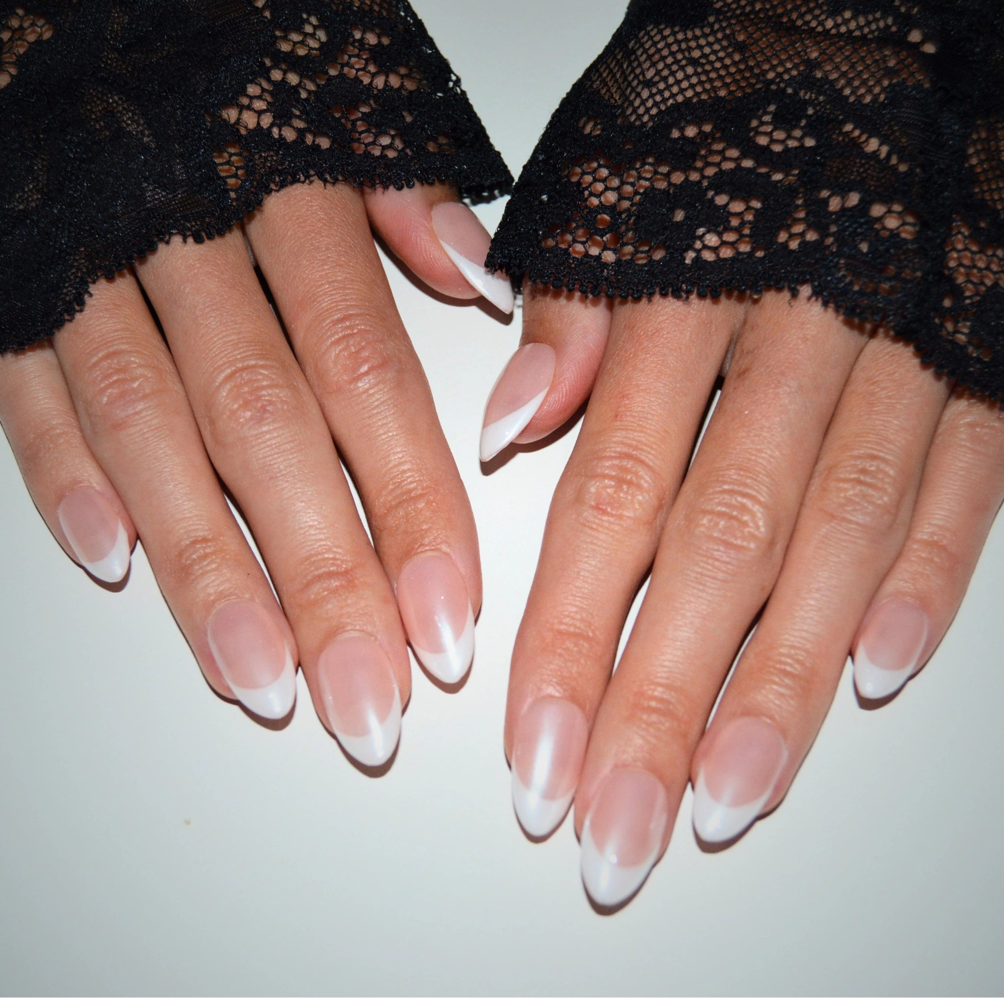 Mains portant les press-on nails Silky French en forme amande, réalisés à la main en gel et acrylique, french blanche élégante sur base nude nacrée.