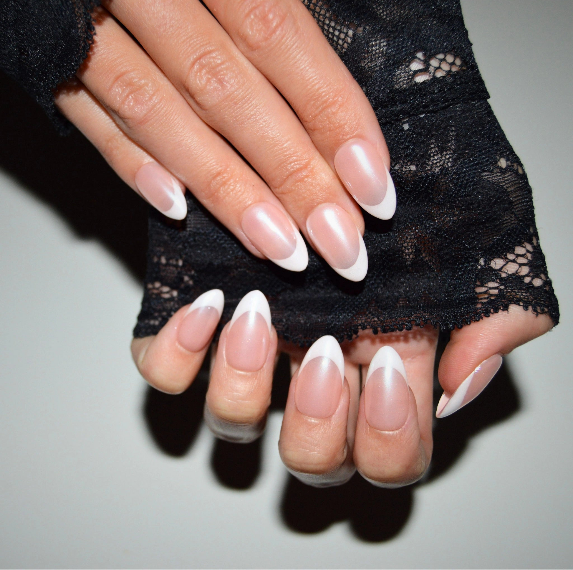 Main repliée mettant en valeur les press-on Silky French faits main en gel et acrylique, french blanche élégante et finition nacrée.