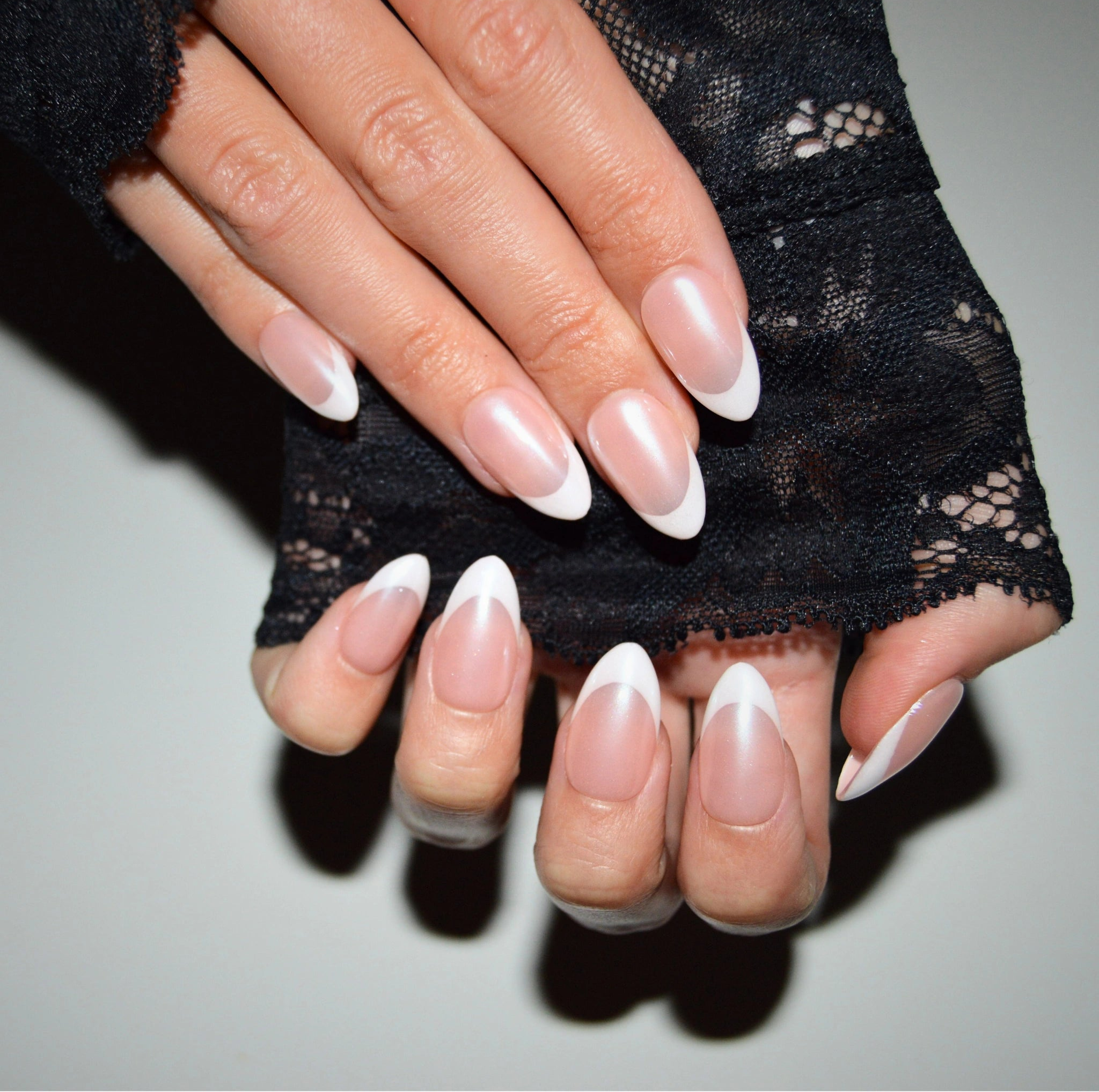 Main repliée mettant en valeur les press-on Silky French faits main en gel et acrylique, french blanche élégante et finition nacrée.